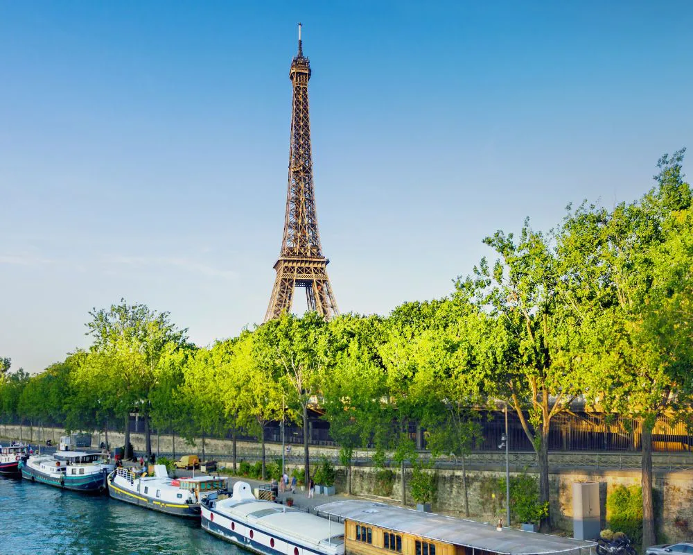 Paris, la tour Eiffel au-dessus des arbres et des péniches amarrées sur les quais de Seine